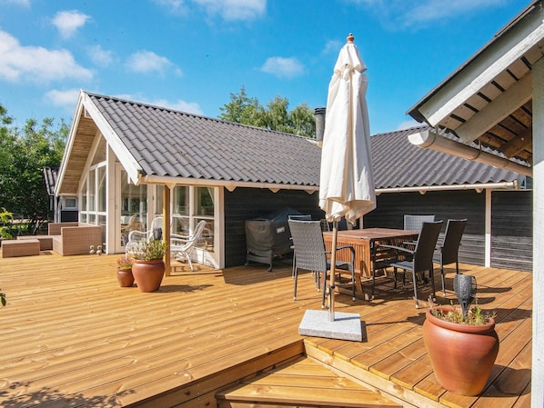 A wooden deck with outdoor furniture, a covered seating area, and potted plants.