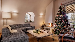 A cozy living room with a fireplace, a plaid sofa, a wooden coffee table, and a Christmas tree. - Villa Prenzano, luxury villa with pool, breathtaking views and concierge service (Greve in Chianti)