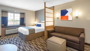 Een hotelkamer met een bed, een bank, een klein tafeltje en een raam met gordijnen.