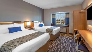 Een hotelkamer met twee bedden, een bureau en een televisie.