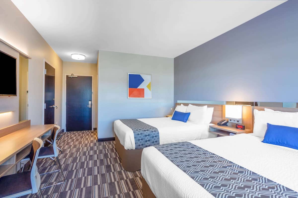 Una habitación de hotel con dos camas, un escritorio y una televisión.