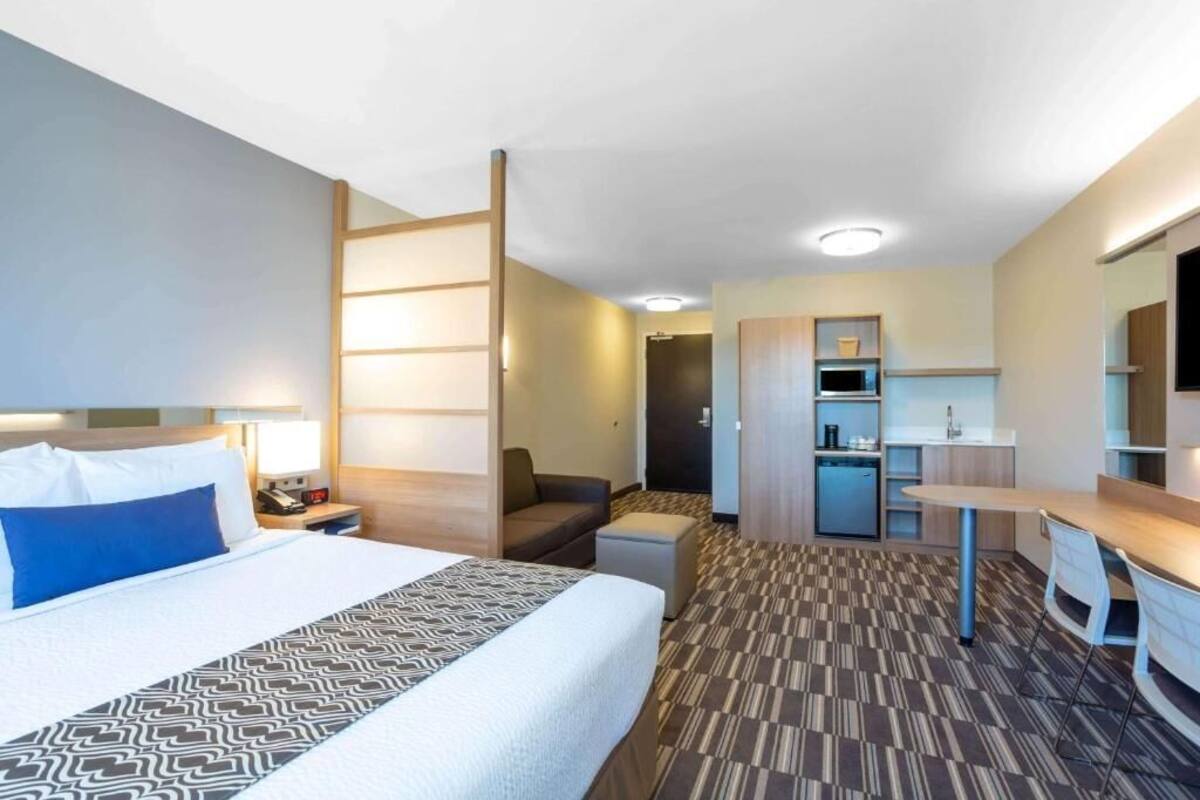 Una habitación de hotel con cama, escritorio, kitchenette y zona de estar.
