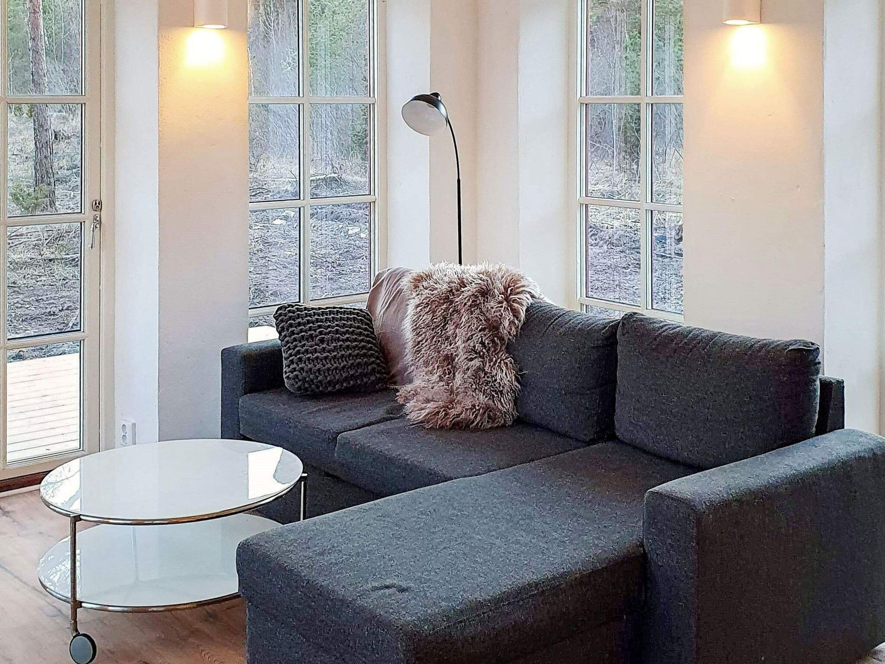A modern living room with a sectional sofa, a round glass coffee table, and a floor lamp.