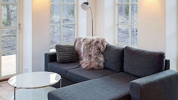A modern living room with a sectional sofa, a round glass coffee table, and a floor lamp.