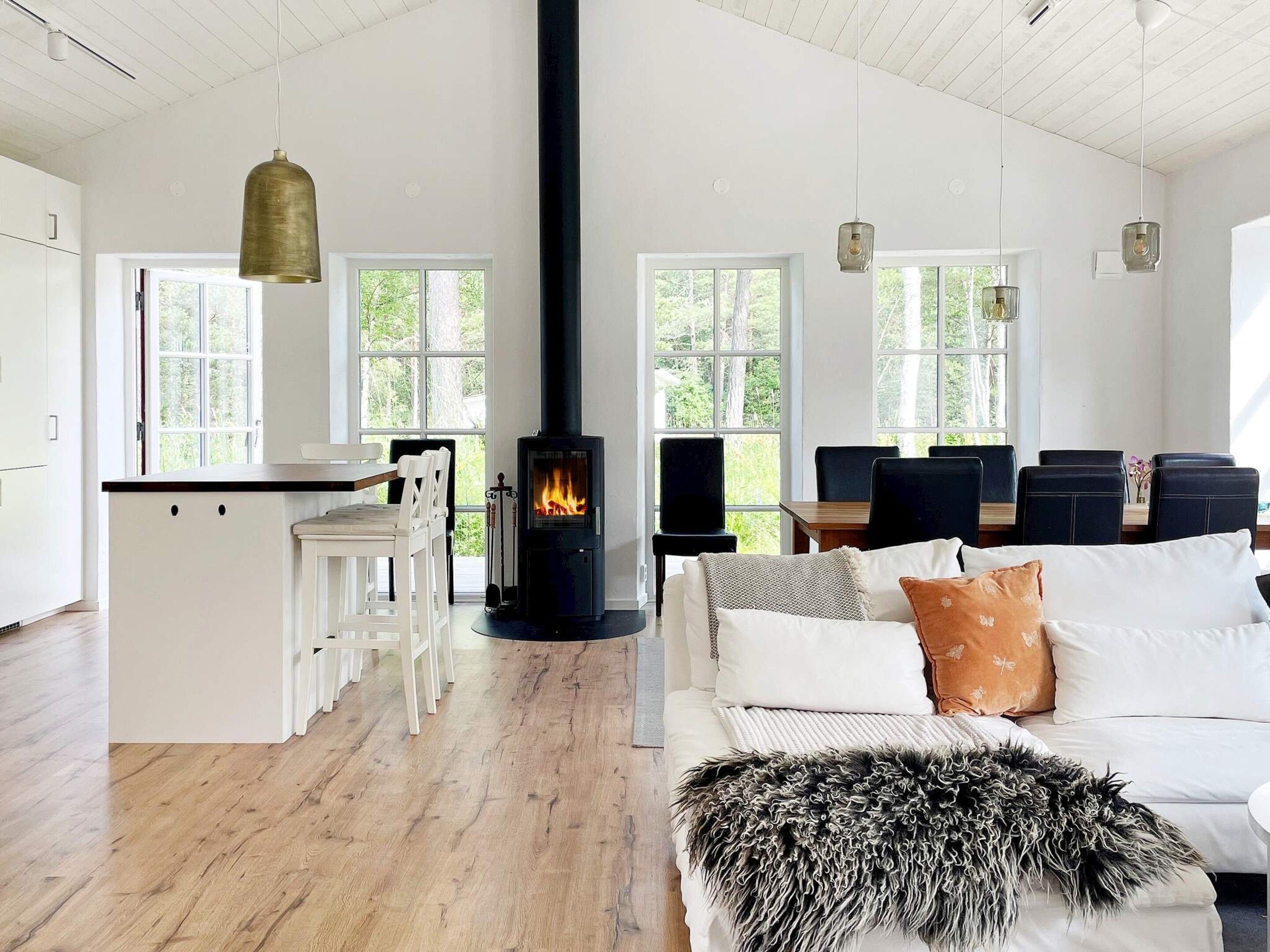 A modern living space with a central fireplace, white furniture, and large windows.