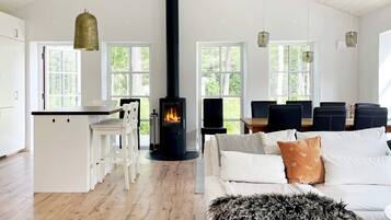 A modern living space with a central fireplace, white furniture, and large windows.