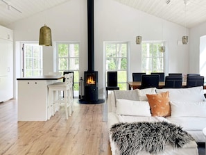 A modern living space with a central fireplace, white furniture, and large windows. - Holiday Home in Katthammarsvik (Katthammarsvik)