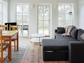 Un salon moderne avec une table à manger en bois, un canapé gris et une petite table ronde.