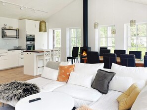 A modern living room with a sofa, a dining area with chairs, a kitchen with appliances, and a fireplace. - Holiday Home in Katthammarsvik (Katthammarsvik)