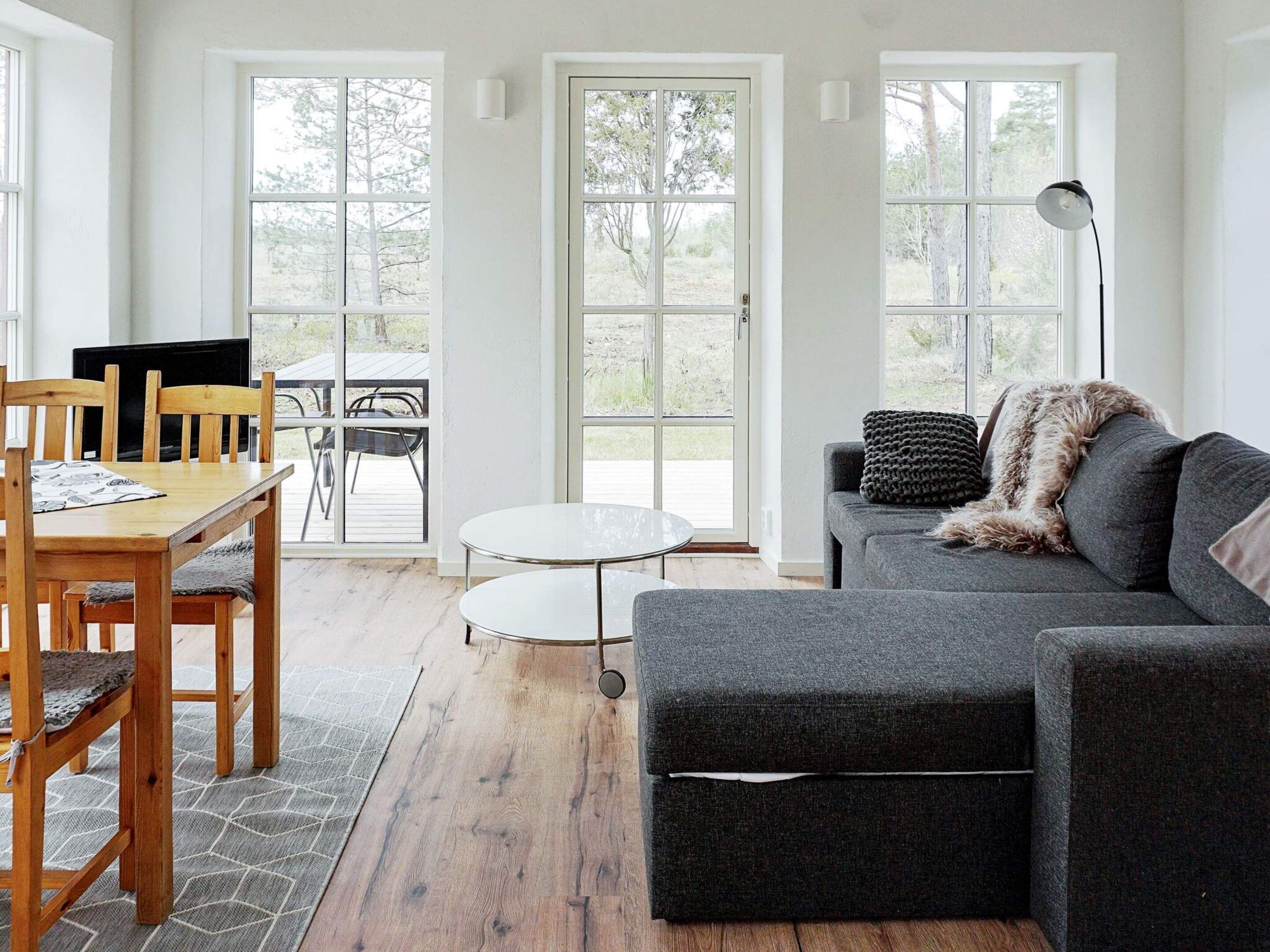 Un salon moderne avec une table à manger en bois, un canapé gris et une petite table ronde.