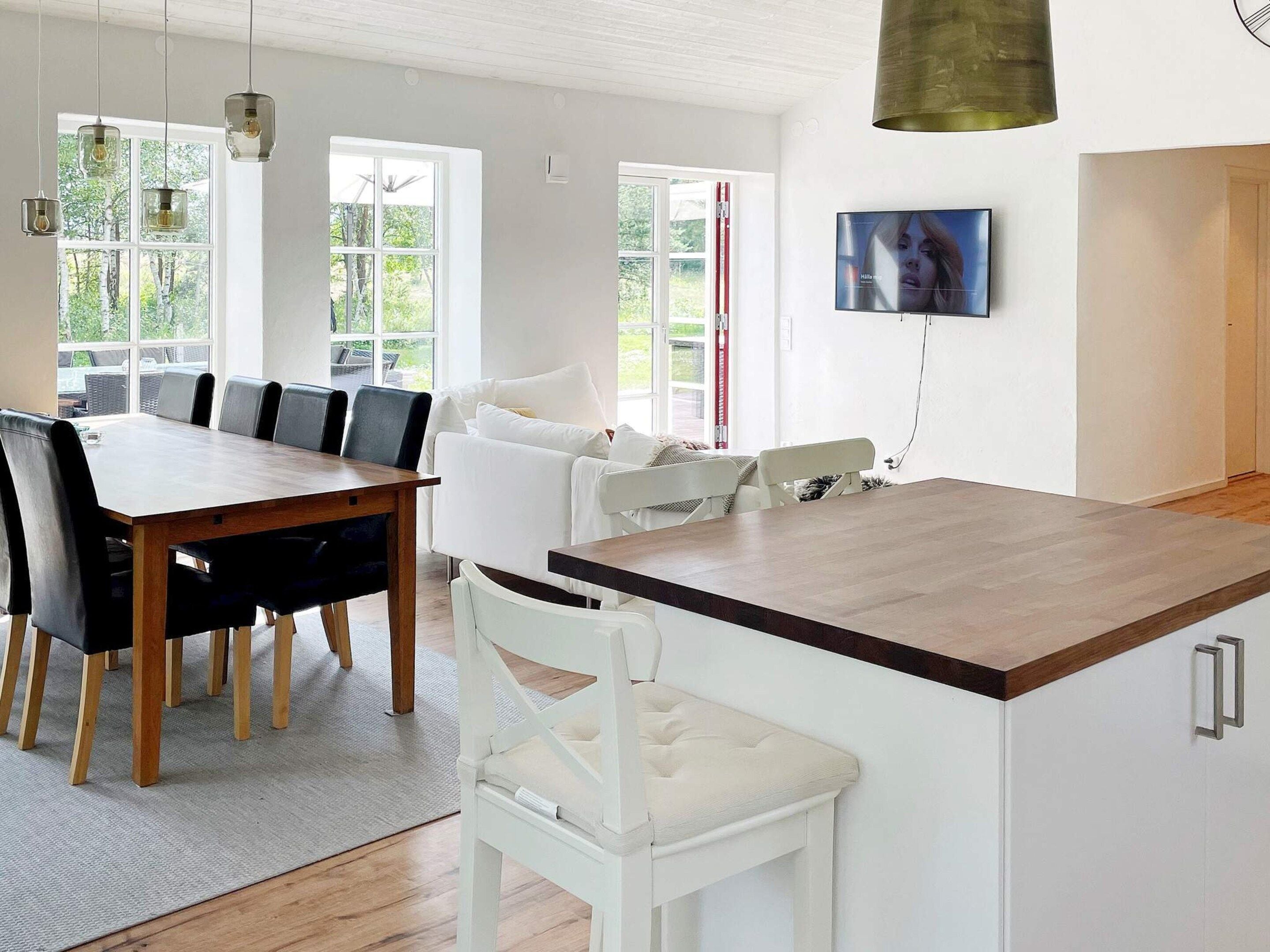 A modern kitchen with a wooden island, white cabinetry, and a dining area with a table and chairs.
