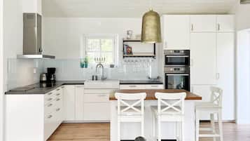 A modern kitchen with white cabinetry, a central island with bar stools, and a hanging pendant light.