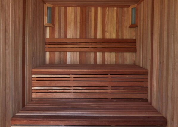 Una sauna de madera con un banco y dos luces fijadas a la pared.