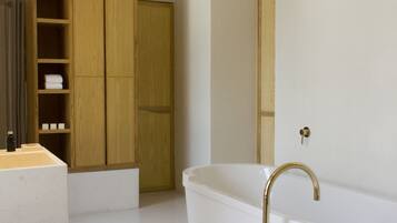 A modern bathroom with a freestanding bathtub, wooden cabinets, and a large mirror.