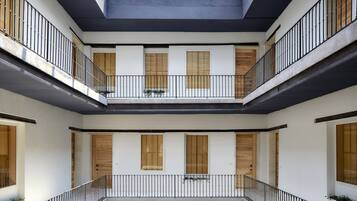 Un interior de varios niveles con balcones, puertas de madera y una escalera central.