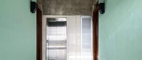 Un couloir avec un plafond en béton, deux portes et un sol brillant.