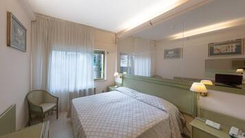 Une chambre d’hôtel équipée d’un lit, d’une chaise, d’un bureau, d’un téléphone et d’une télévision.