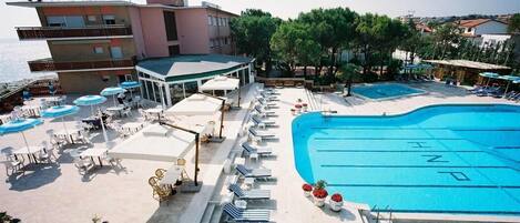 Una piscina al aire libre de temporada, sombrillas, tumbonas