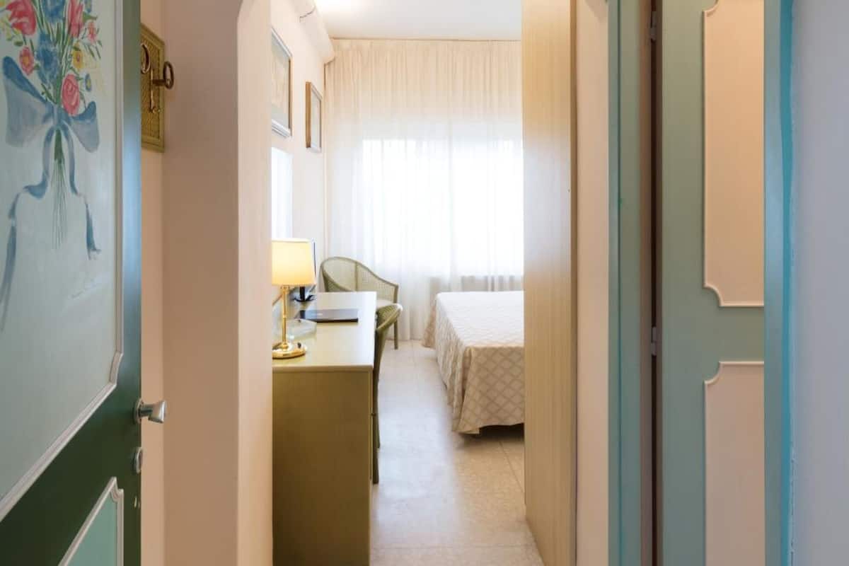 A hotel hallway with a bed, a desk, and a chair.