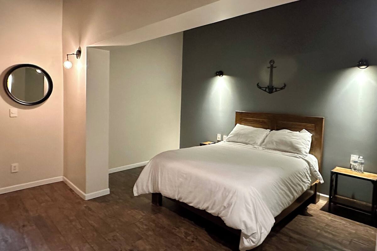 A bedroom with a wooden bed, a round mirror, and two wall-mounted lights.