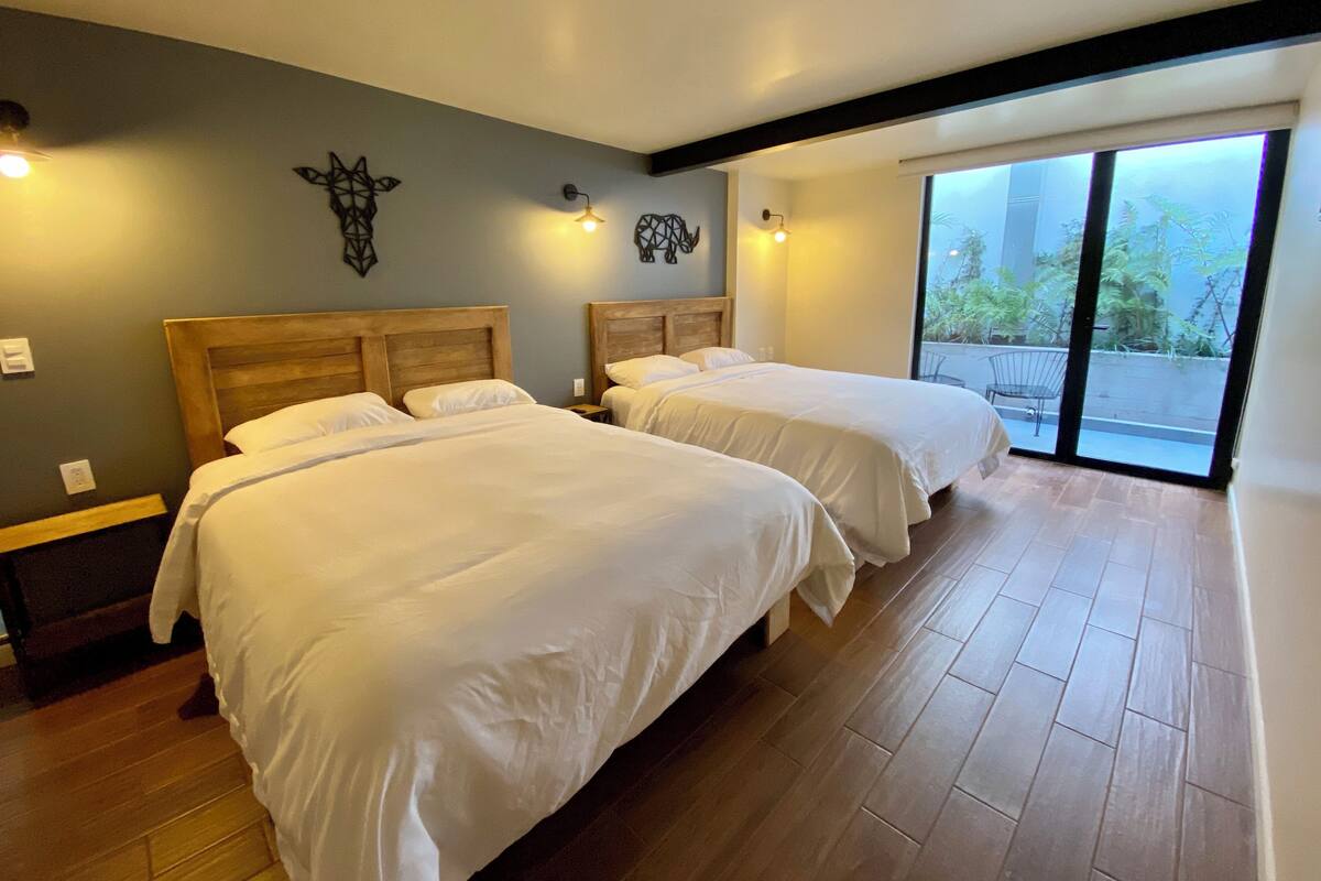A hotel room with two beds, wooden headboards, and a large sliding glass door leading to a balcony.