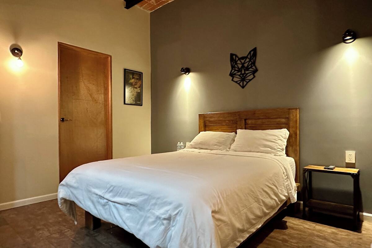 A bedroom with a wooden headboard, a white bedspread, and two bedside tables.