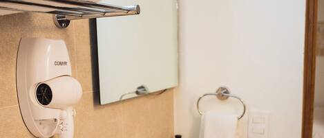 A bathroom with a sink, mirror, towel rack, and a hairdryer on the wall.