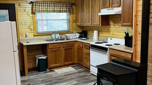 A compact kitchen with wooden cabinets, a stove, and a sink.