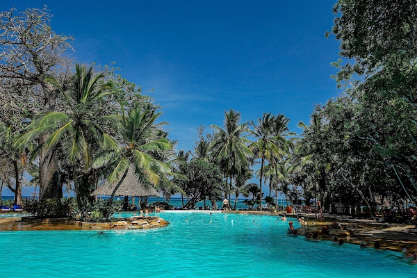 Una piscina al aire libre, sombrillas, sillones reclinables de piscina