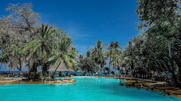 Una piscina al aire libre, sombrillas, tumbonas