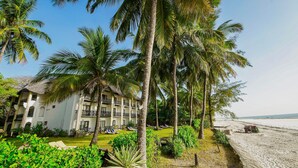 A resort with a pool, palm trees, and a beach. - Papillon Lagoon Reef (Diani Beach)
