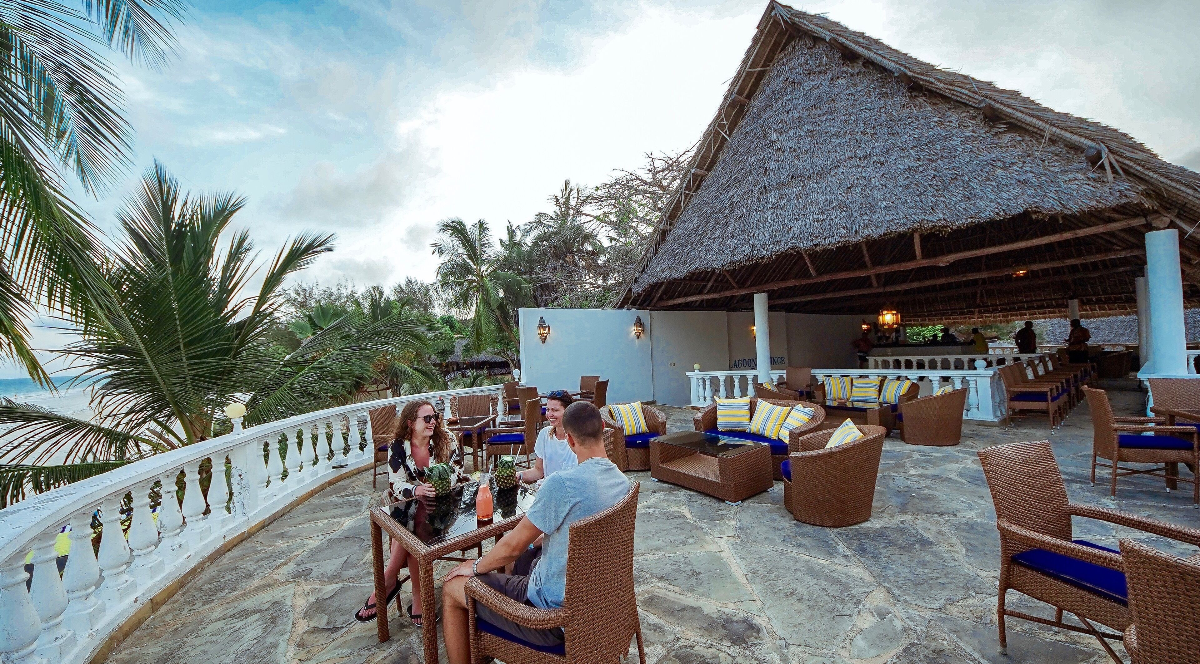An outdoor seating area with wicker furniture and a thatched roof structure.