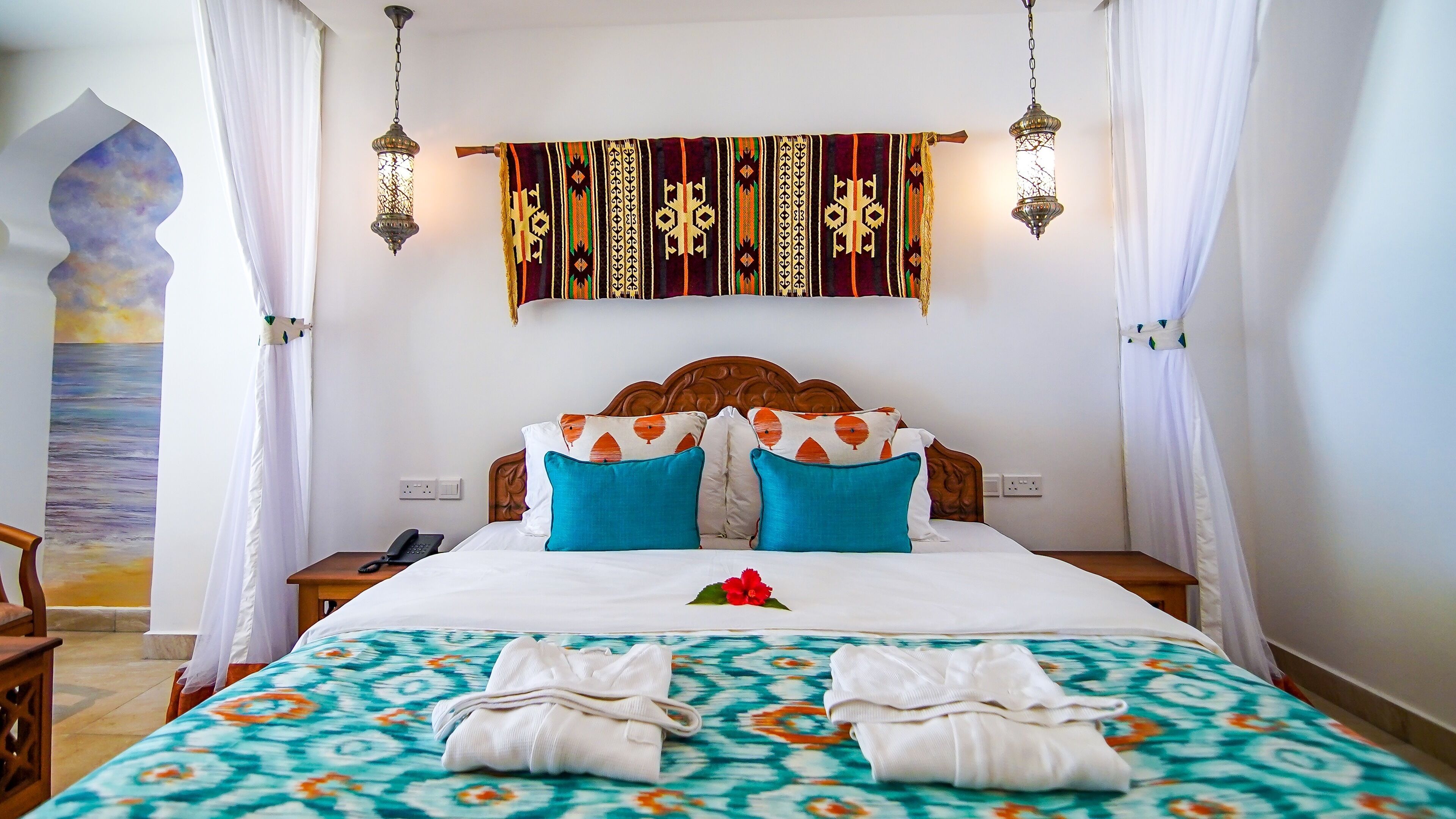 Una cama bien hecha con una colcha estampada, dos almohadas y un cabecero decorativo.