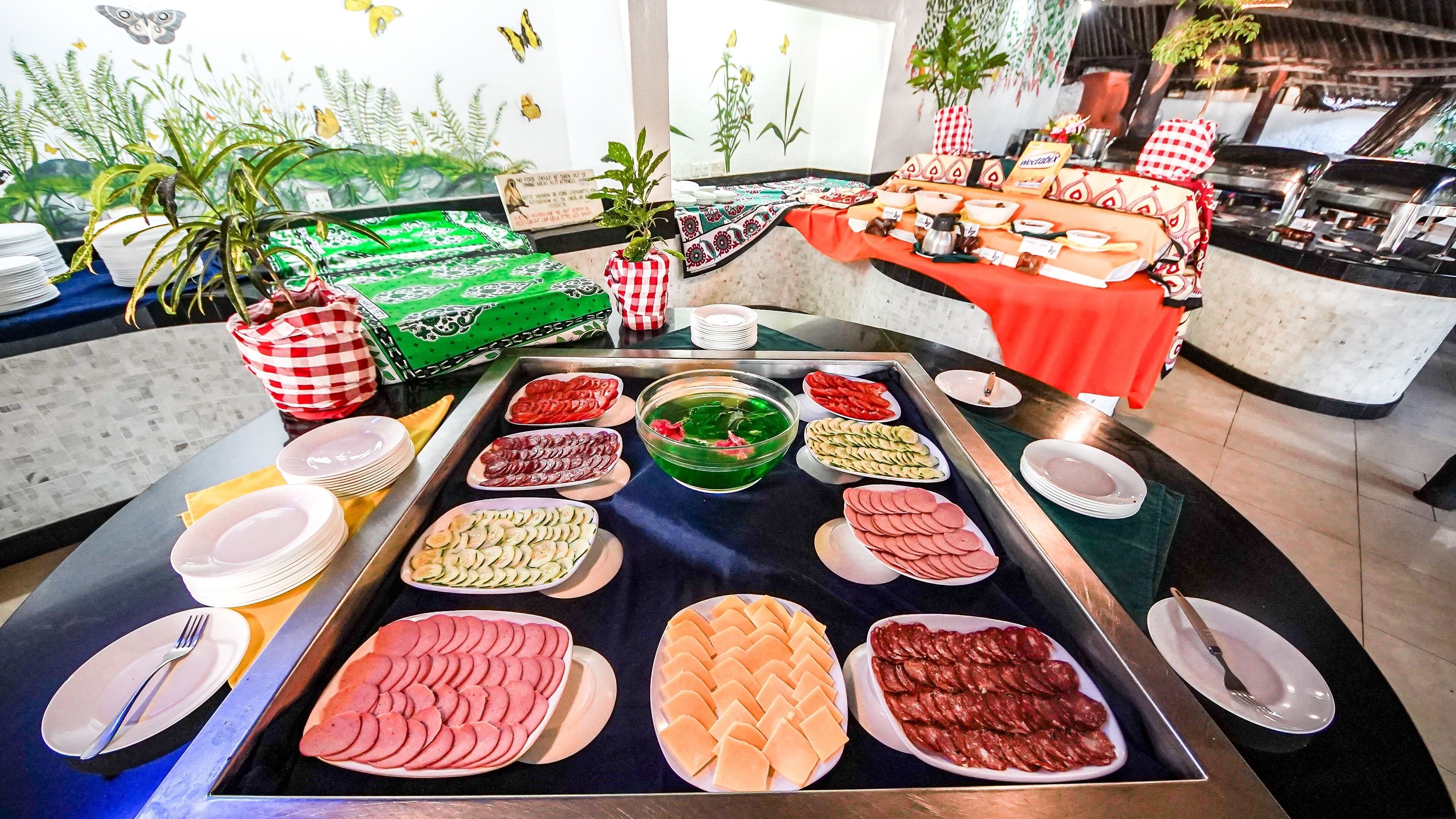 A buffet with various food items and a decorative wall with butterfly decals.
