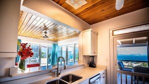 Eine moderne Küche mit großem Fenster, Blick auf einen Balkon und Deckenventilator.