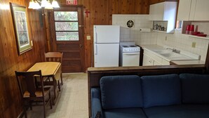 Una cocina compacta con una mesa de comedor, sillas, un sofá azul y un refrigerador.