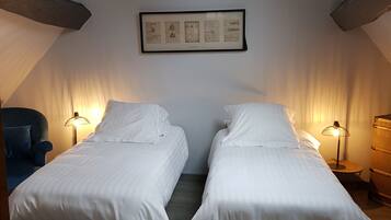 Une chambre avec deux lits, une lucarne et une œuvre d’art encadrée au mur.