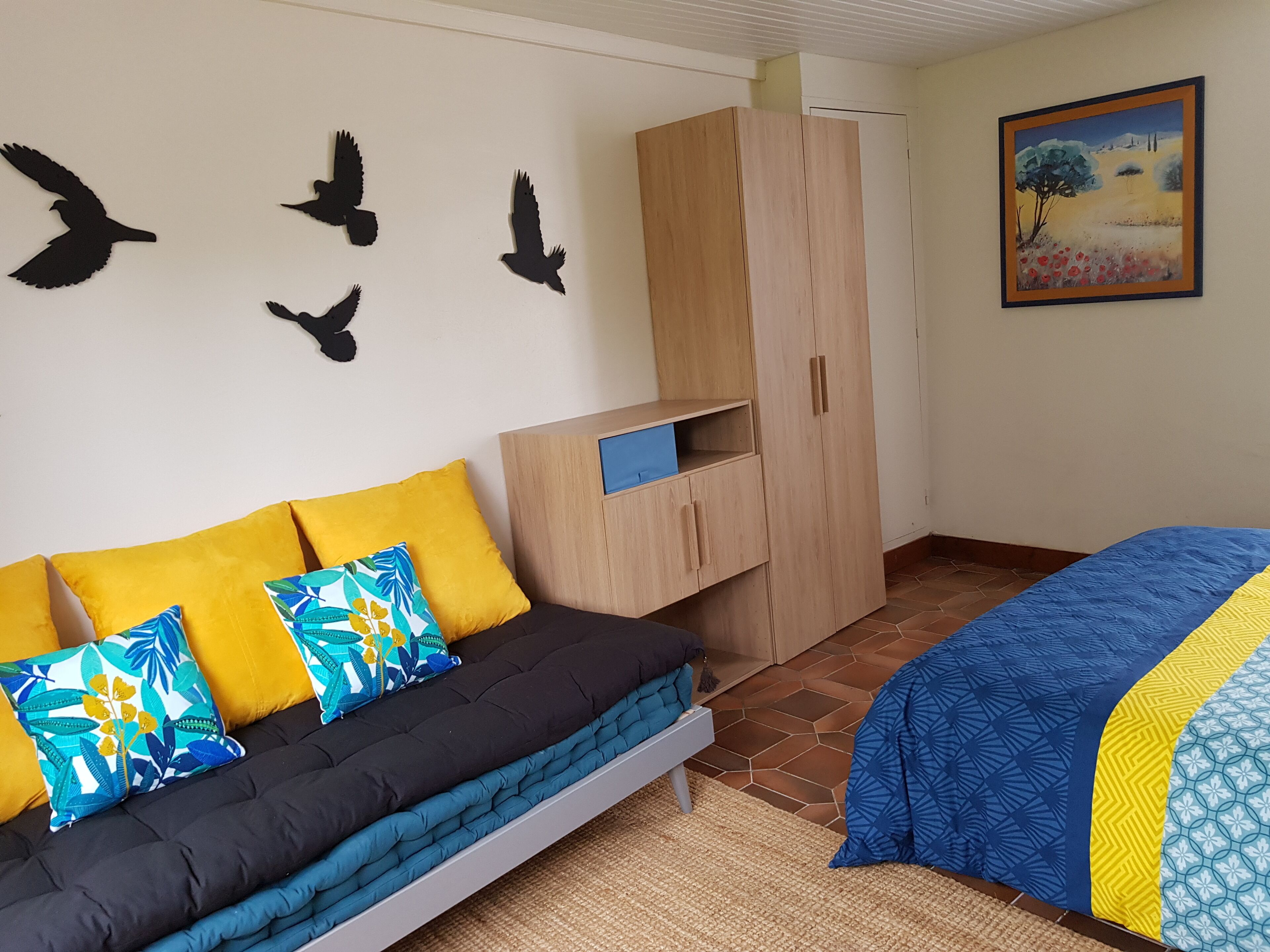 A bedroom with a bed, a sofa, a wardrobe, and wall art.