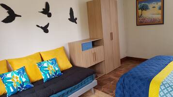 A bedroom with a bed, a sofa, a wardrobe, and wall art.