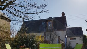 Una casa con techo inclinado, chimenea visible y una ventana pequeña.