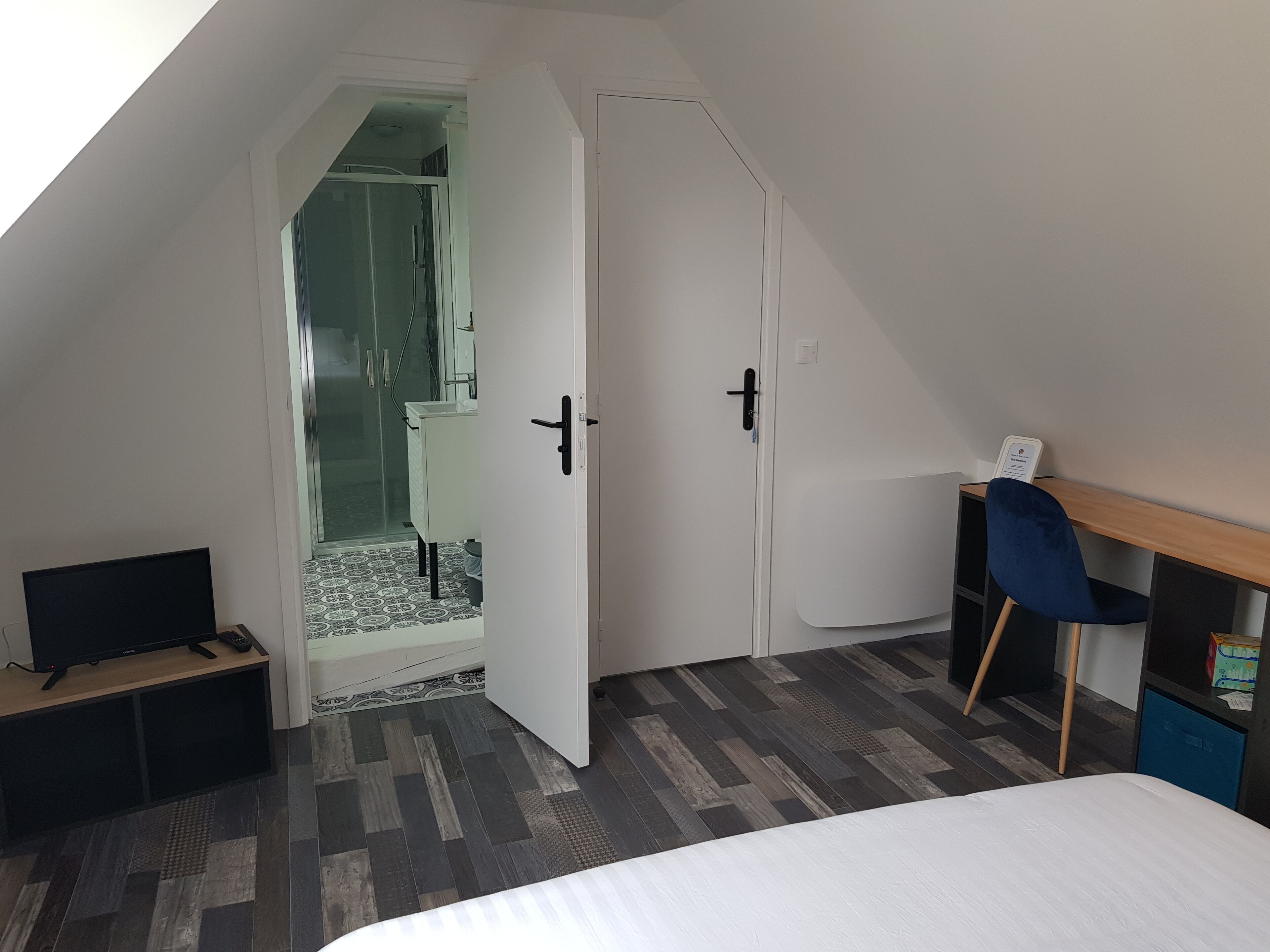 A bedroom with a bed, a desk, a chair, and a wardrobe.