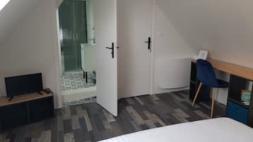 A bedroom with a bed, a desk, a chair, and a wardrobe.