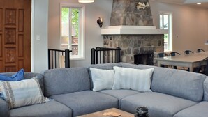 Una sala de estar moderna con chimenea de piedra, un sofá seccional y una mesa de centro de madera.