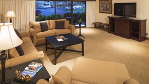 A hotel room with a sofa, armchair, coffee table, lamp, TV, and a view of the street through the window. - Beautiful Two Bedroom Condo w/ all the amenities!  (Palm Harbor)