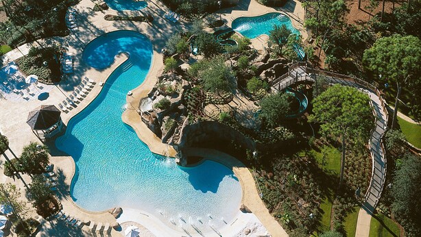 An aerial view of a resort with multiple swimming pools, sun loungers, and a well-maintained landscape. - Beautiful Two Bedroom Condo w/ all the amenities!  (Palm Harbor)