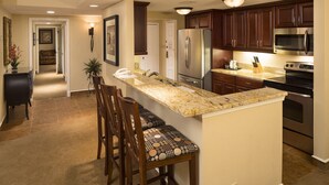 A kitchen with a central island, dark wooden cabinets, stainless steel appliances, and a marble countertop. - Beautiful Two Bedroom Condo w/ all the amenities!  (Palm Harbor)