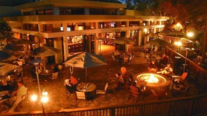 An outdoor dining area with multiple tables and chairs, umbrellas, and a central fire pit. - Beautiful Two Bedroom Condo w/ all the amenities!  (Palm Harbor)