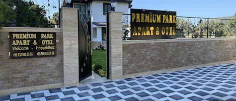 A gated entrance with a sign for "Premium Park Apart & Otel" and contact numbers.