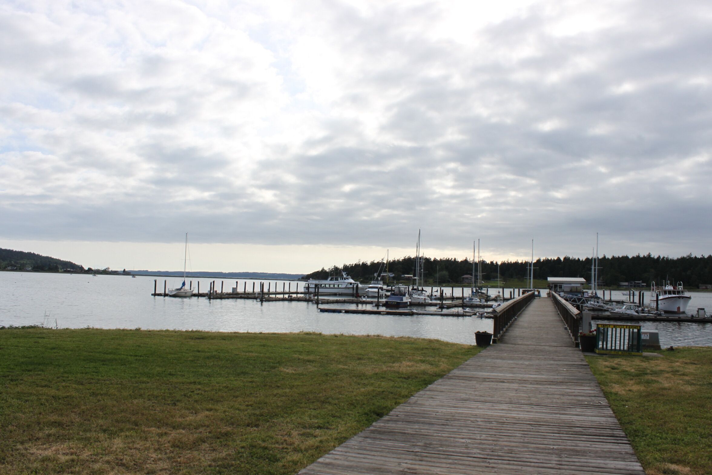 A wooden pier leading to a marina with boats docked.