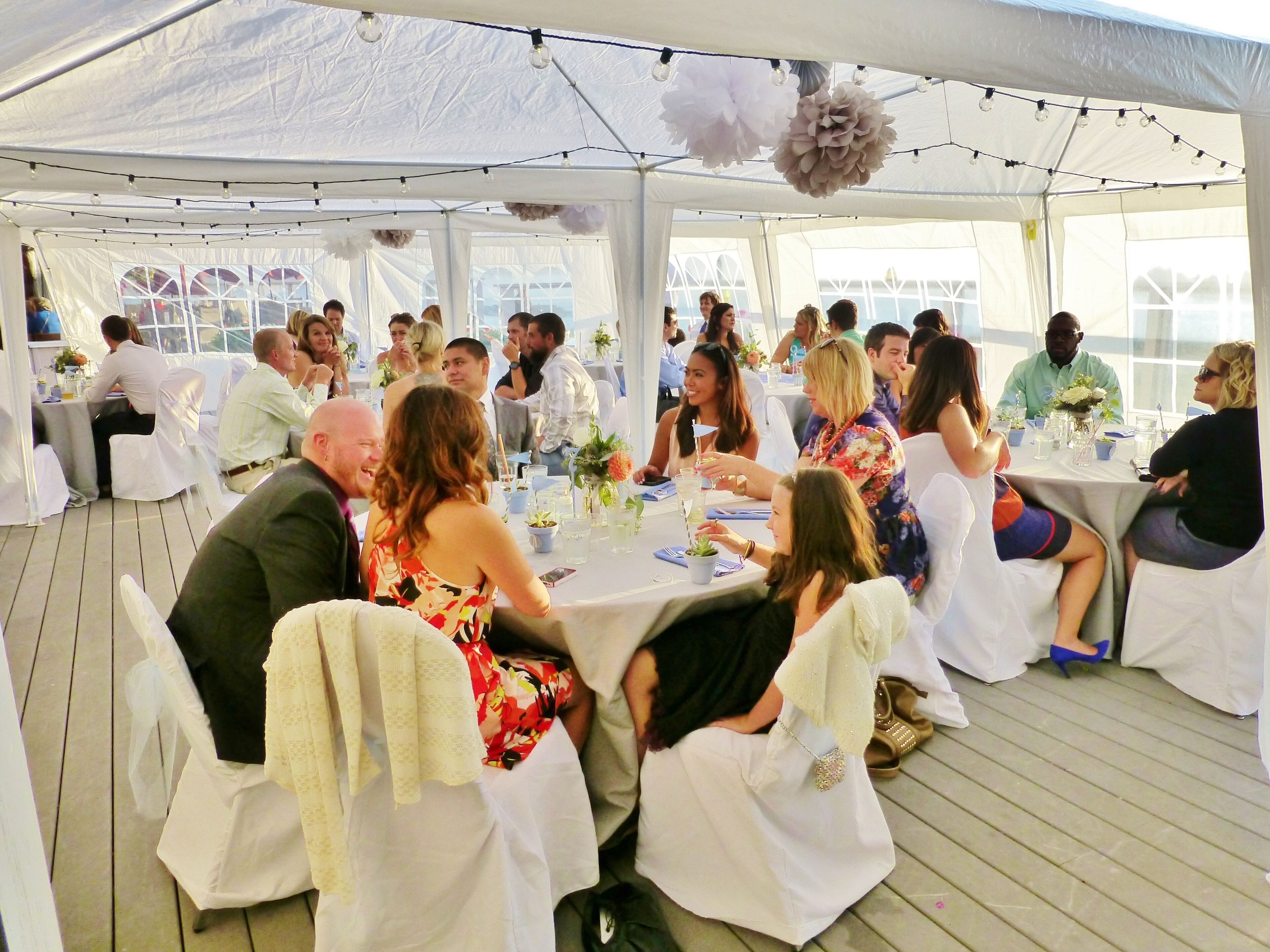 Un espacio para eventos con carpas, mesas dispuestas para invitados, manteles blancos y centros de mesa florales.